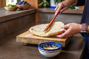 Long wooden spreader buttering garlic bread
