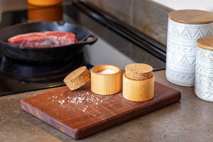 two salt cups on a cutting board next to stove 