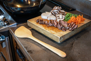 wok spatula on the counter next to stir fry meat and veggies next to wok