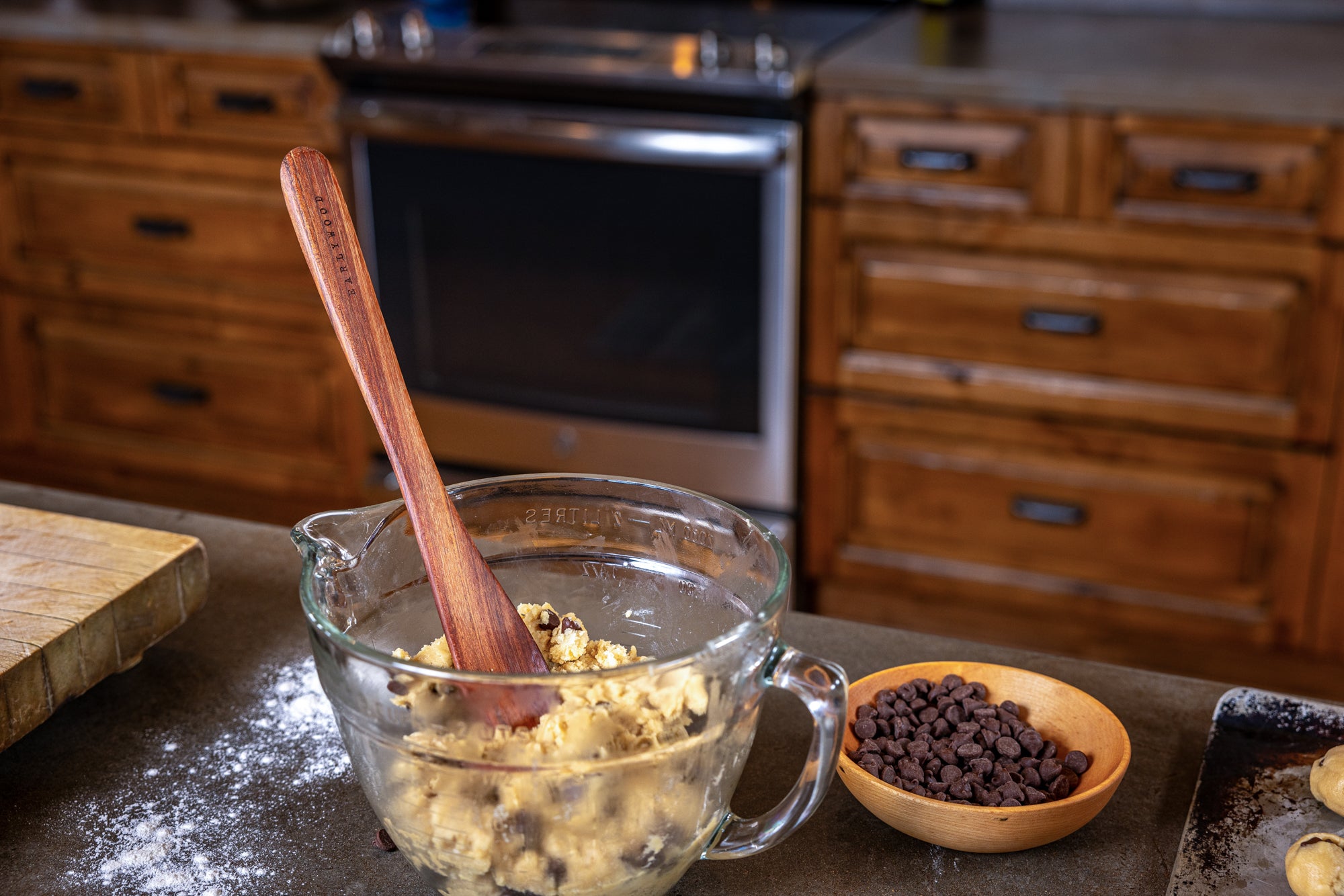 long wooden spreader sticking out of a bowl of chocolate chip cookie dough 