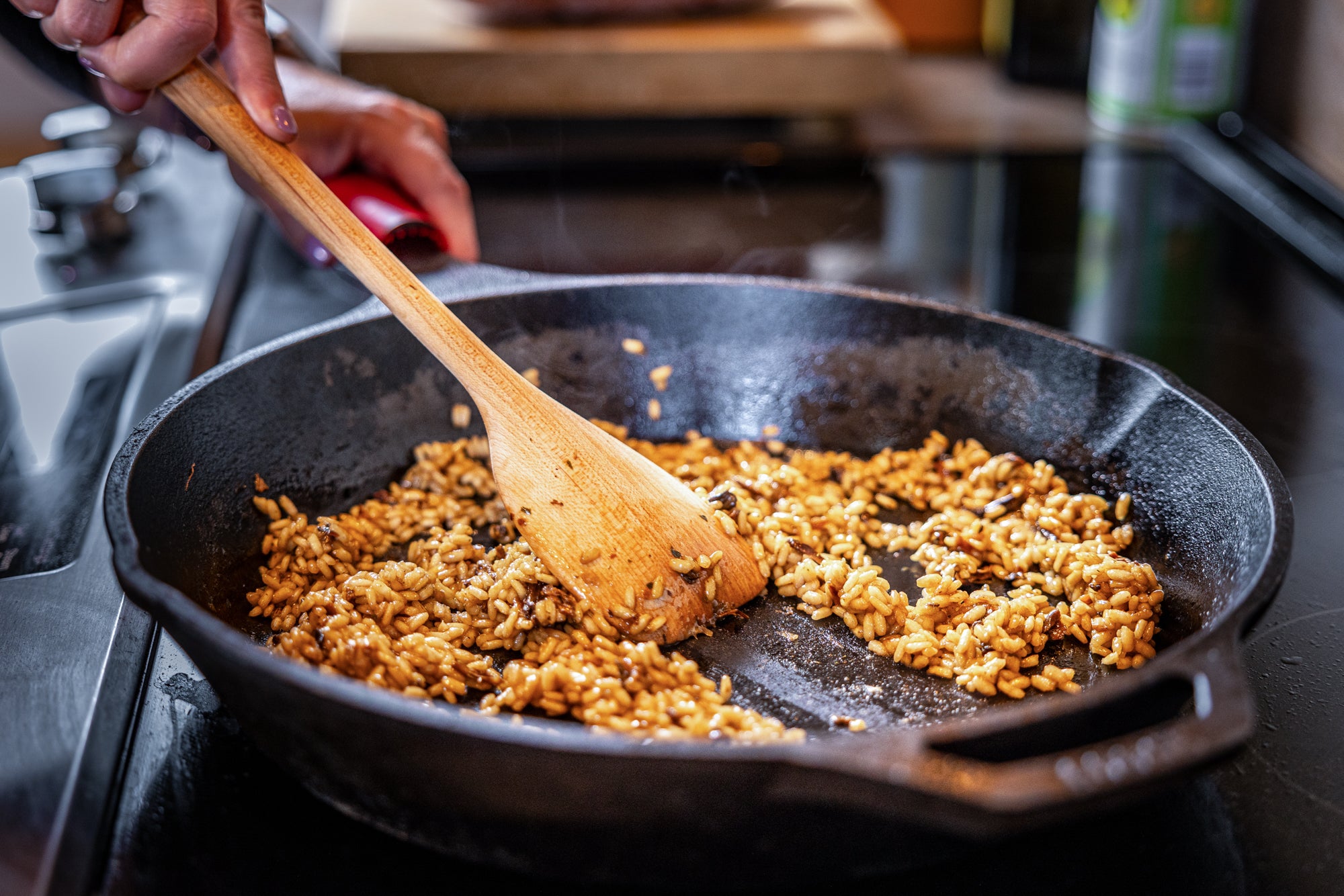 scraper spoon clearing a patch in risotto in cast iron pan