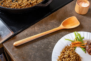 scraper spoon on counter next to stove top and plate of food