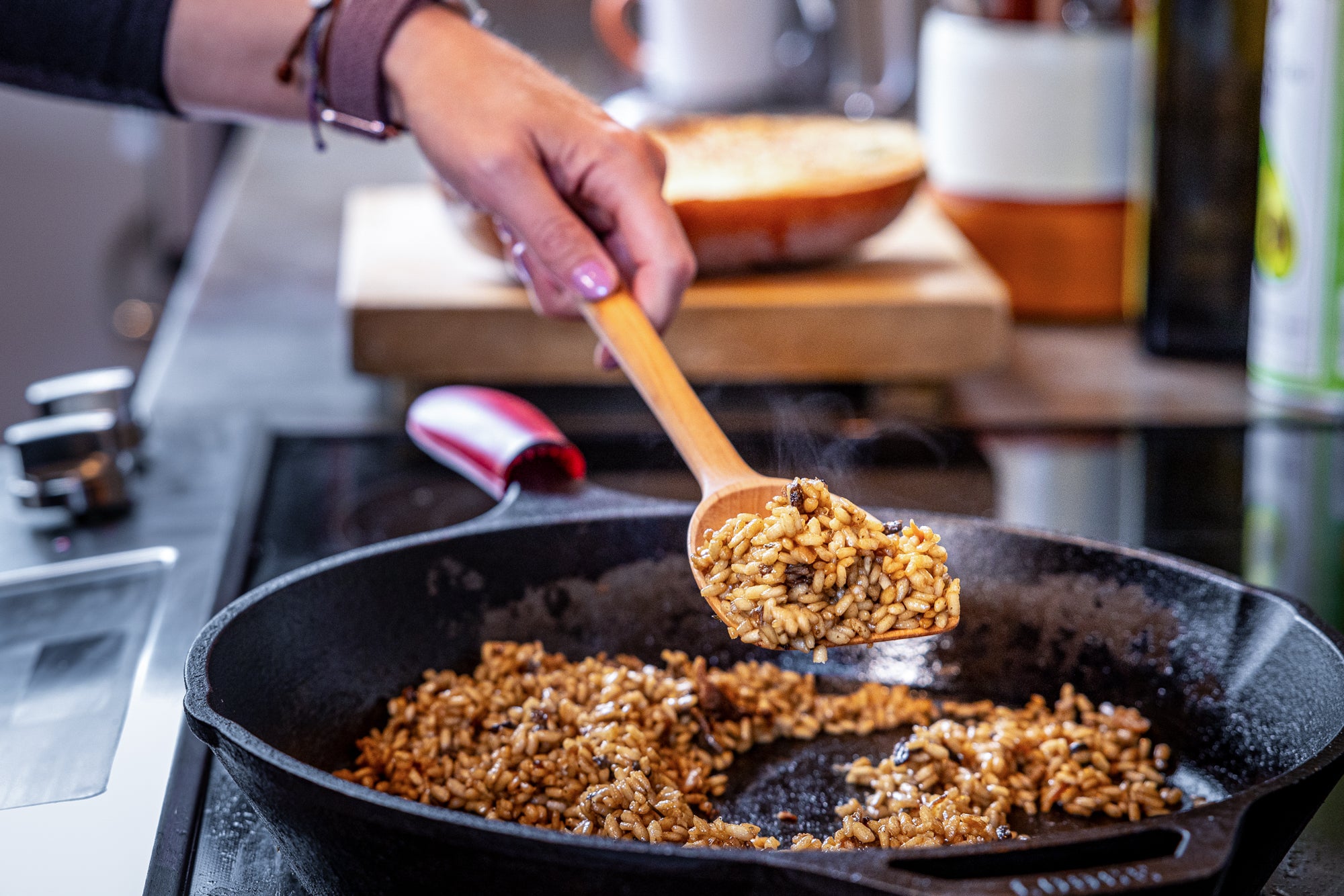 Scraper spoon scooping risotto over in cast iron pan