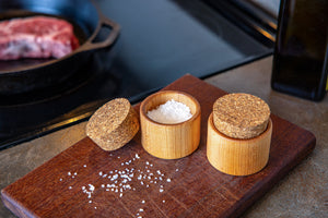 close up of two salt cups on a cutting board next to stove