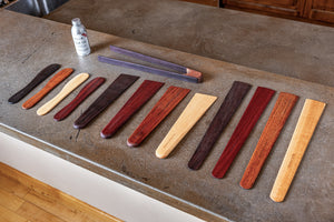 wooden spatulas, scrapers and spreaders with wooden tongs and wood oil spread out on a counter