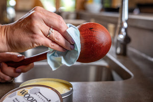 applying wood wax to ladle with open tin of wax