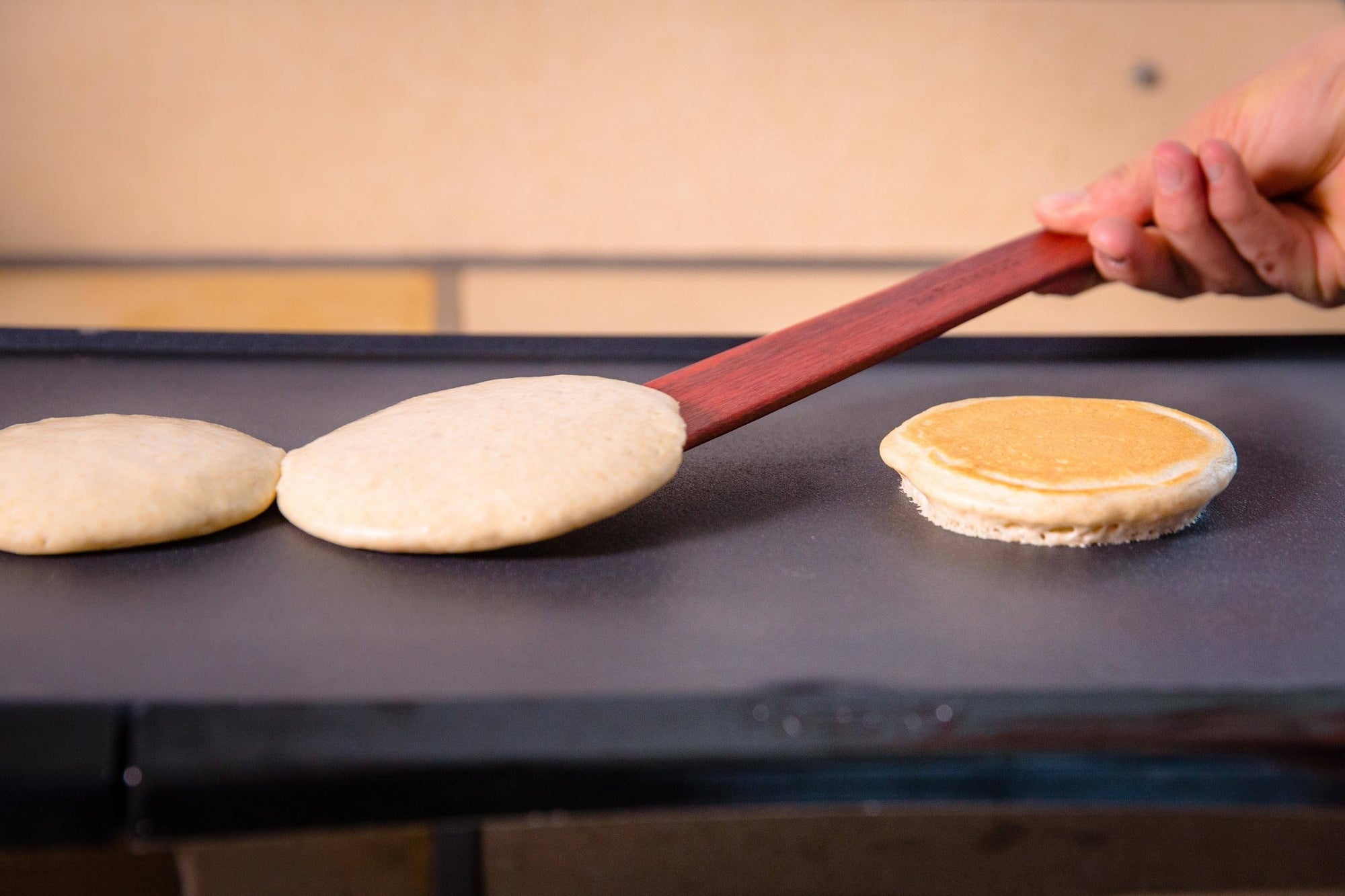 flipping pancakes with thin wooden spatula - Earlywood
