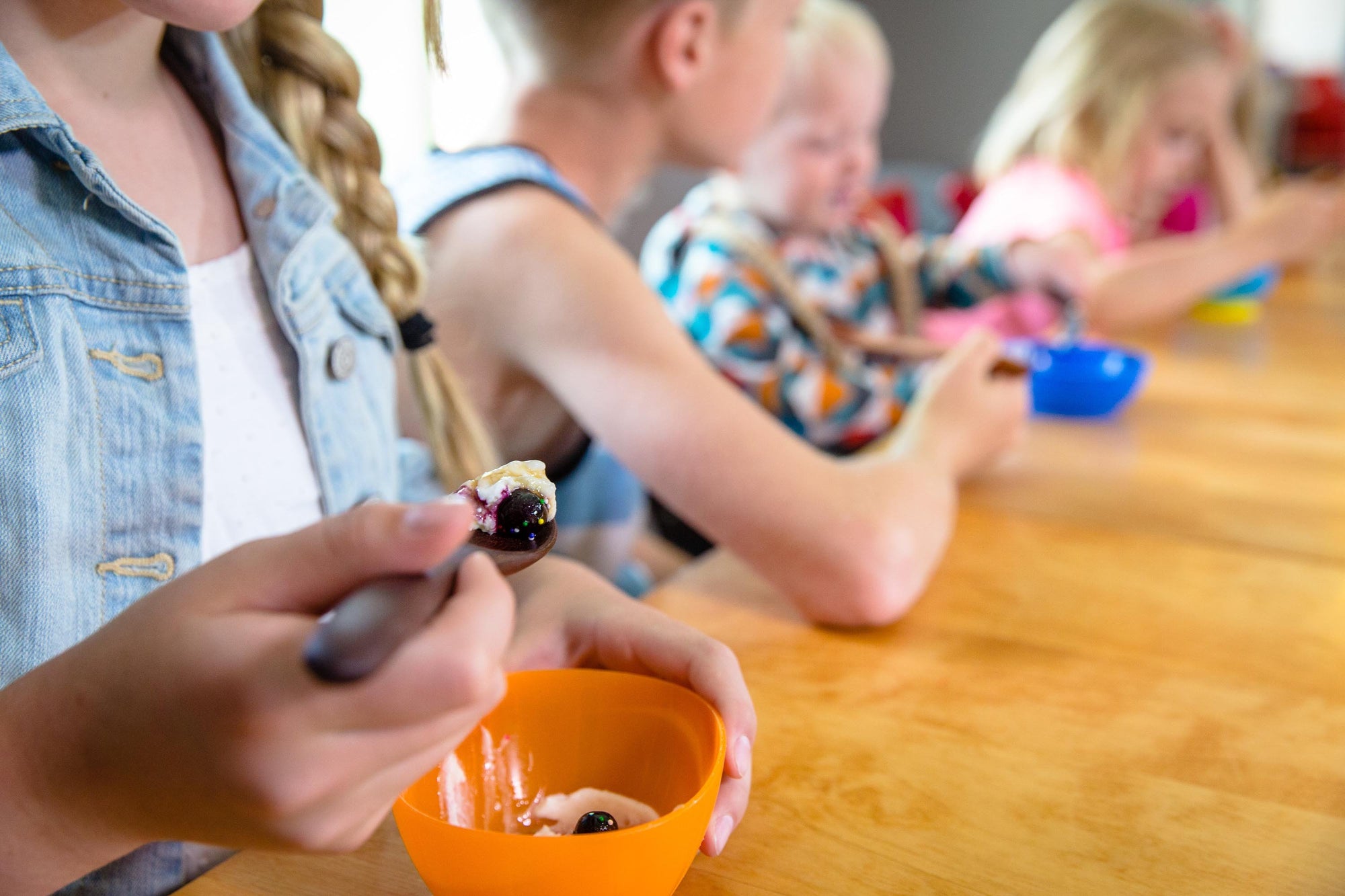 line of kids using customized wooden spoons for eating yogurt - Earlywood