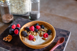 wooden bowl with yogurt and fruit with wooden spoon